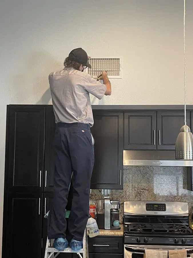 Technician inspecting an air vent during HVAC service in Venersborg